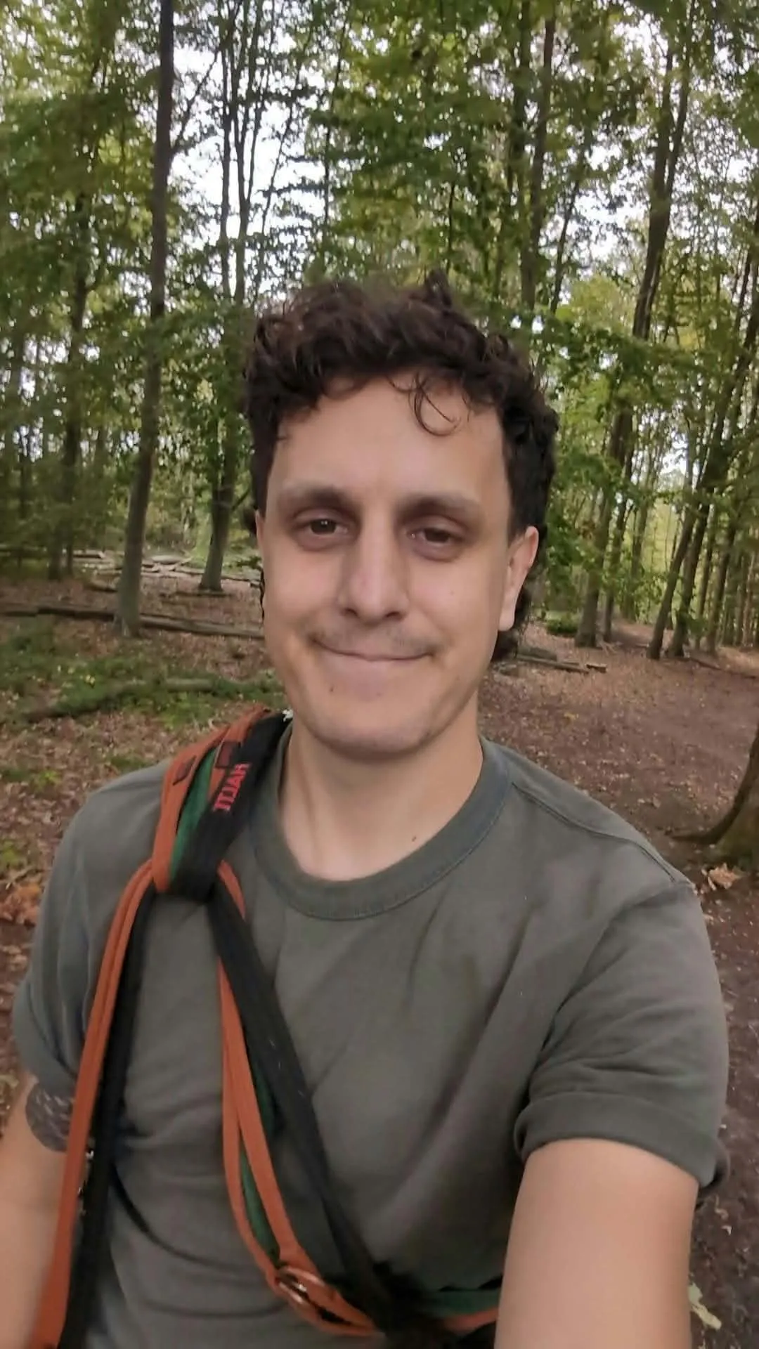 Joe smiling in a woodland clearing, with dog leads slung over his shoulder